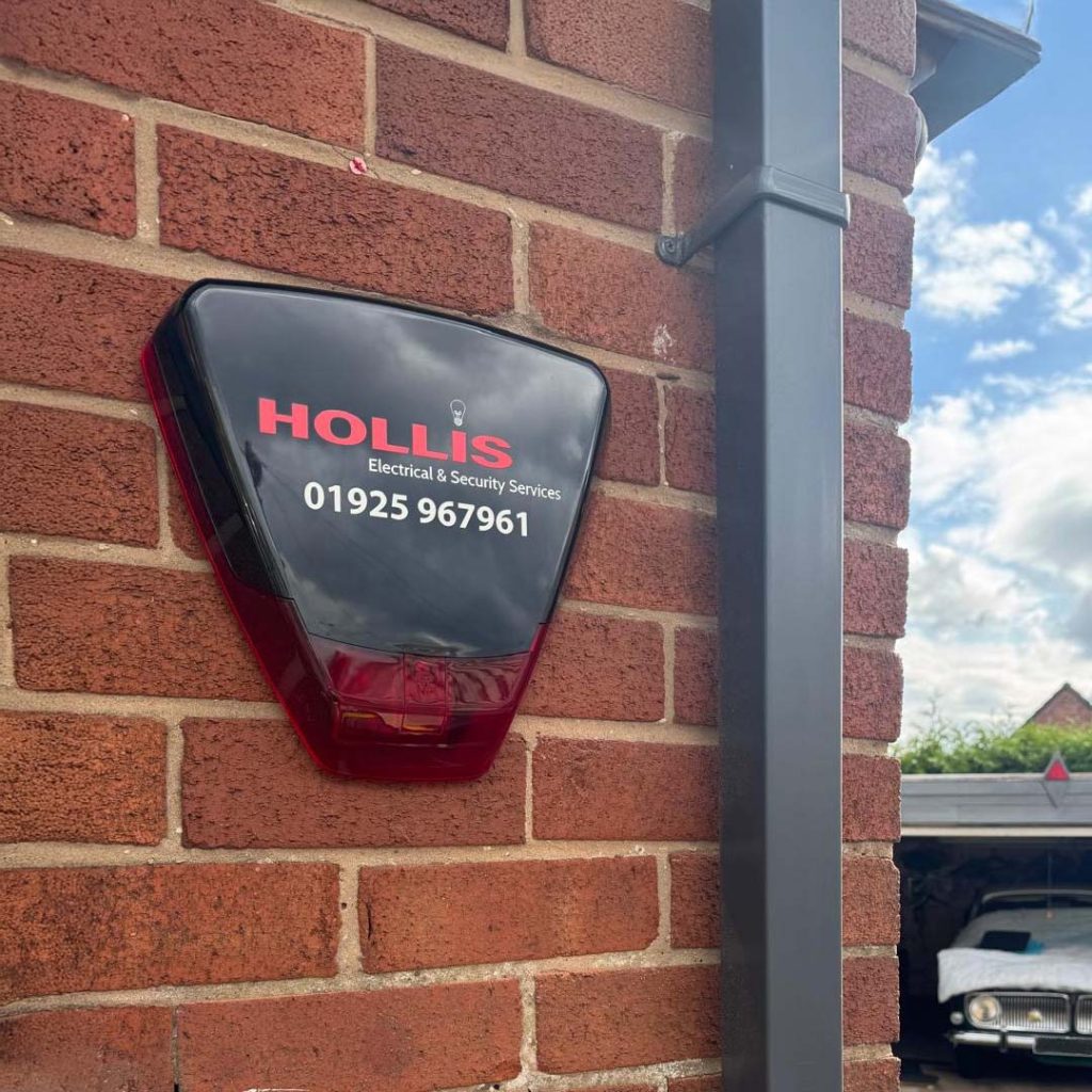 Home alarm system featuring Hollis branding fitted on outside external wall.